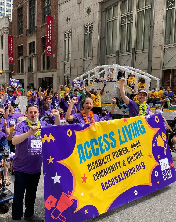 Access Living staff and supporters celebrate in a parade holding a large purple and yellow banner.
